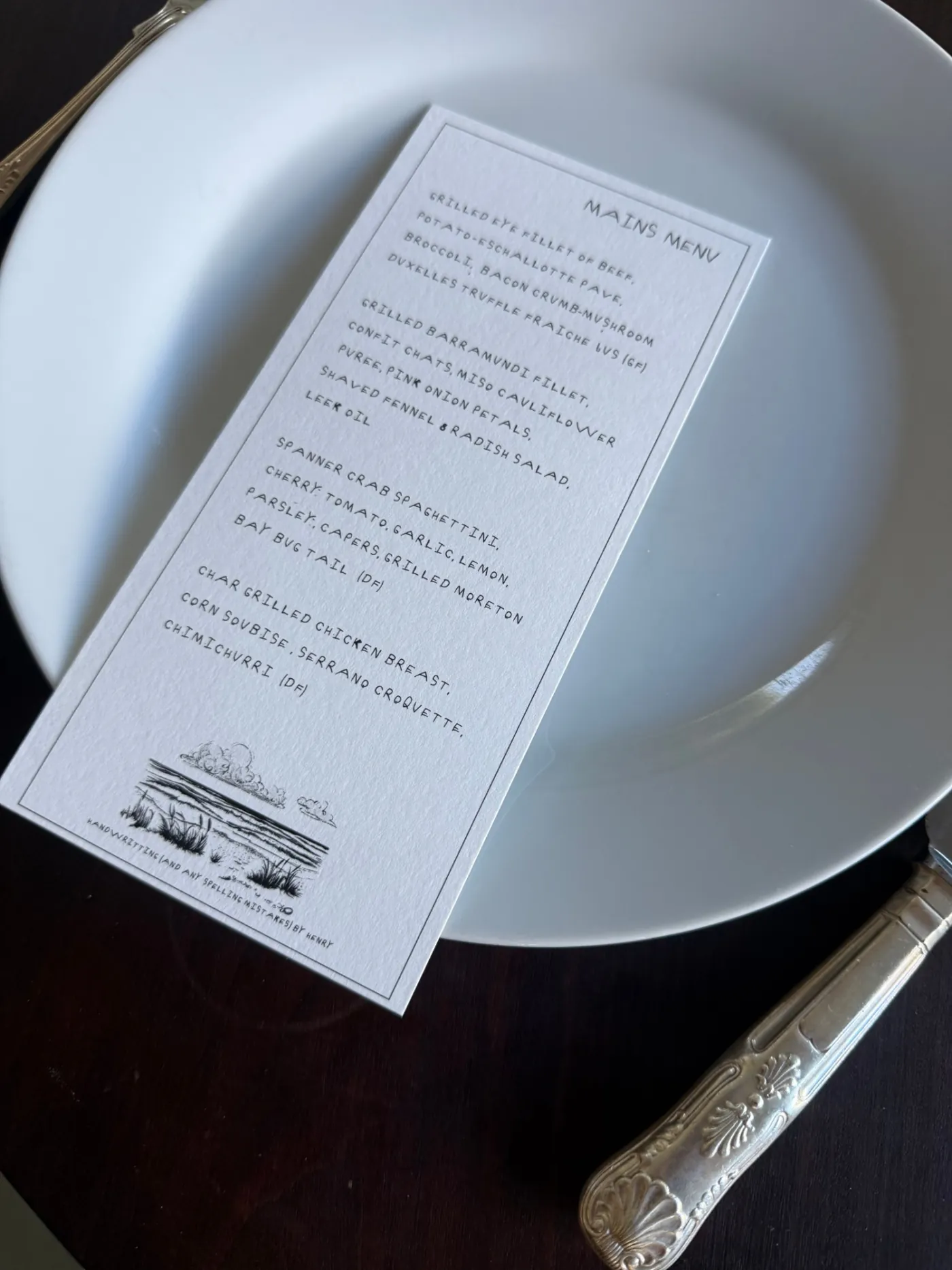 Mains menu card set in a custom handwritten font with a thin black border
