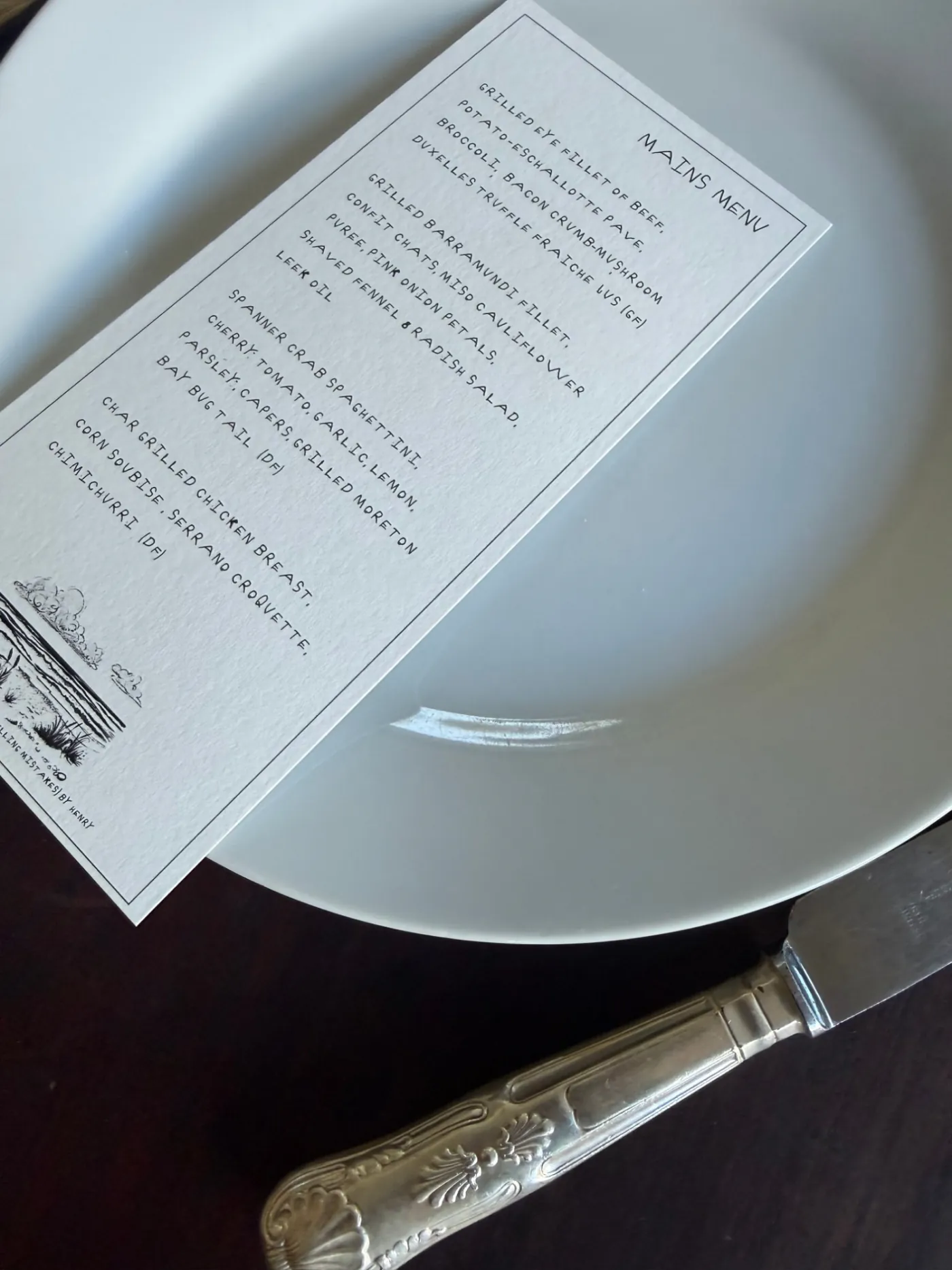 Mains menu printed in a custom handwritten font, resting on a dinner plate